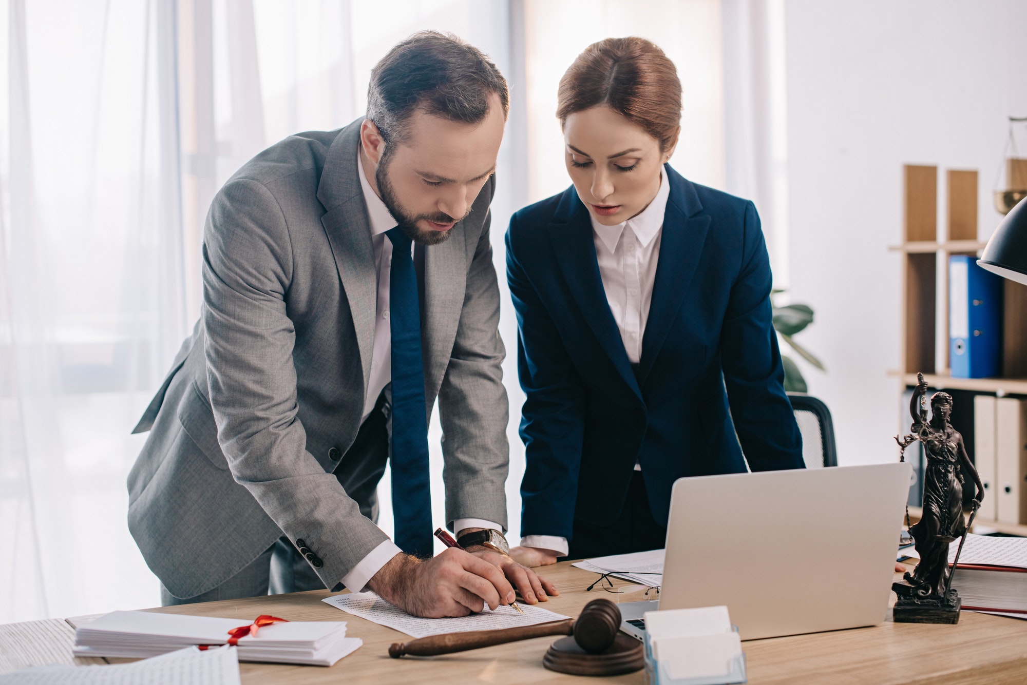 lawyers-in-suits-working-together-on-project-at-workplace-with-gavel-and-laptop-in-office