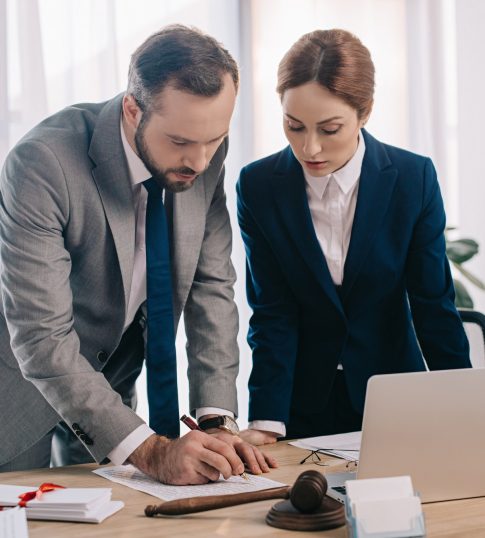 lawyers-in-suits-working-together-on-project-at-workplace-with-gavel-and-laptop-in-office